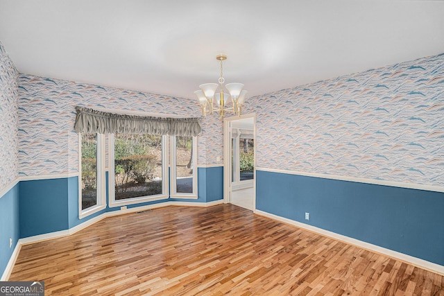 unfurnished dining area featuring wood-type flooring and a chandelier