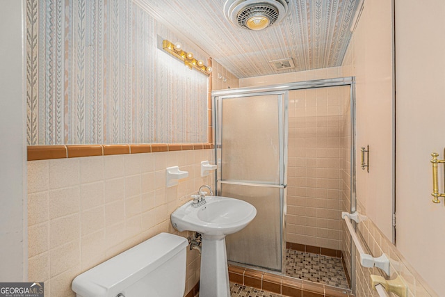 bathroom featuring tile walls, toilet, and walk in shower