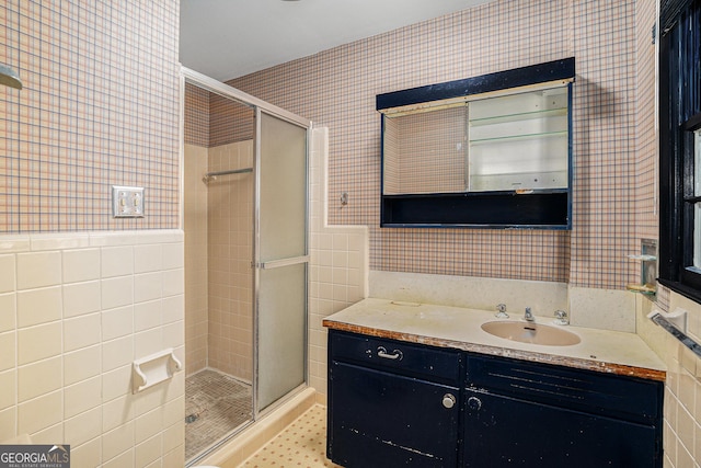 bathroom with vanity, a shower with shower door, and tile walls