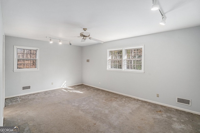 spare room with track lighting, ceiling fan, and carpet