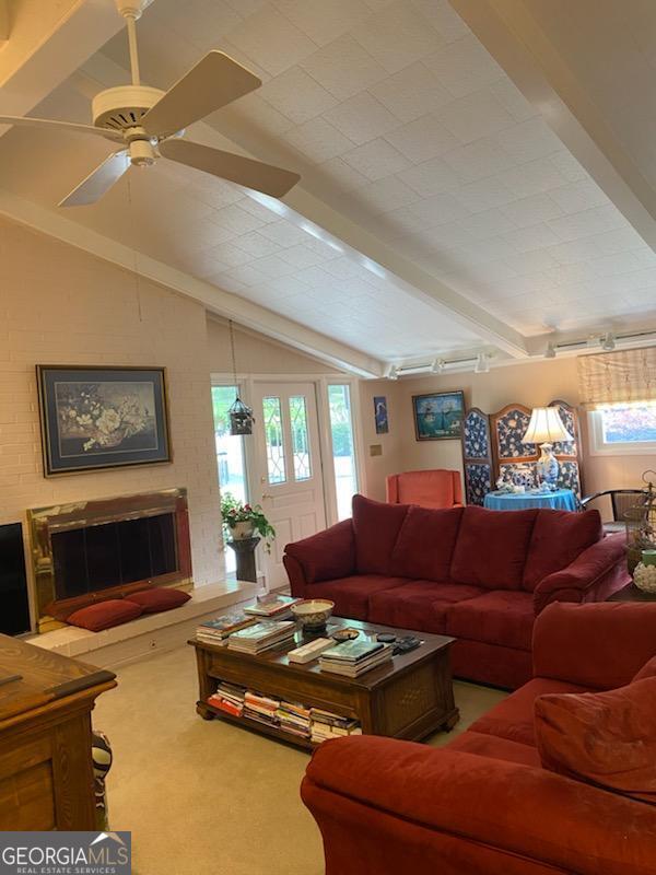 living room featuring lofted ceiling with beams, ceiling fan, carpet flooring, and a fireplace