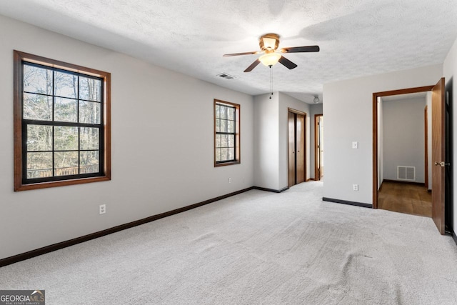 spare room featuring carpet floors, baseboards, visible vents, and a textured ceiling