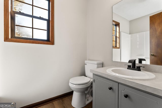 bathroom featuring toilet, baseboards, wood finished floors, and vanity