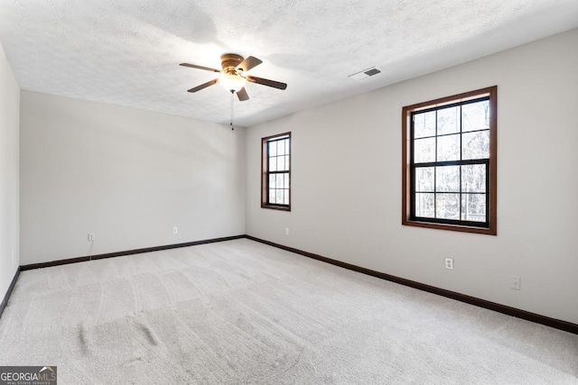 spare room with light carpet, a textured ceiling, and baseboards