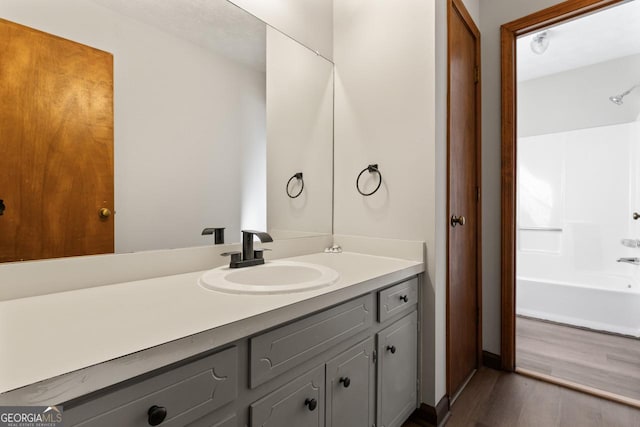 full bath with bathing tub / shower combination, vanity, and wood finished floors