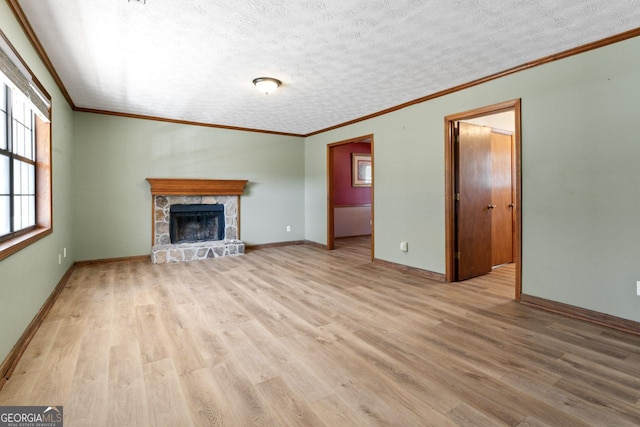 unfurnished living room with light wood-style floors, baseboards, a textured ceiling, and a stone fireplace