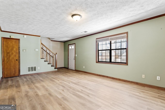 entrance foyer featuring light wood-type flooring, stairs, visible vents, and ornamental molding