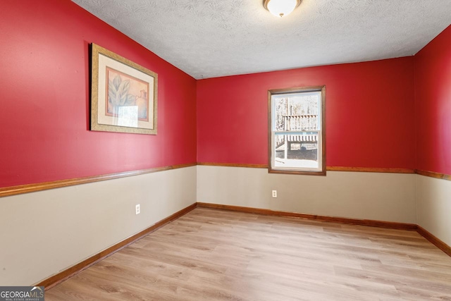 unfurnished room featuring a textured ceiling, baseboards, and wood finished floors