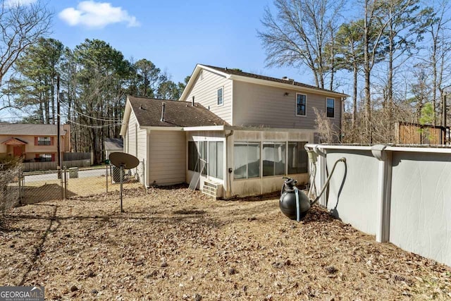 rear view of house featuring a gate, fence, and a sunroom