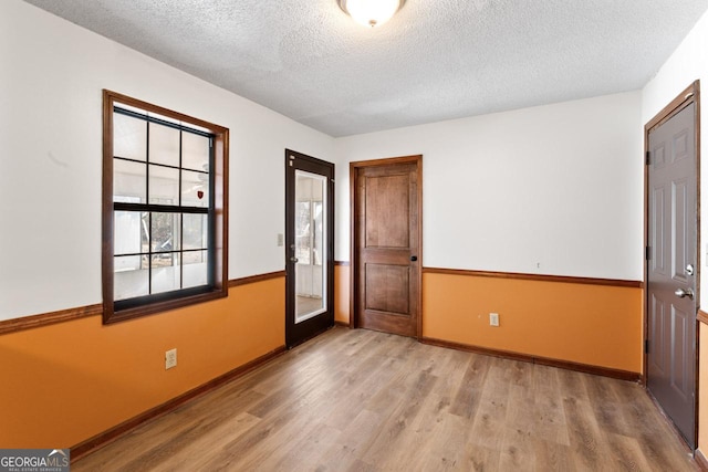 interior space featuring a textured ceiling, wood finished floors, and baseboards