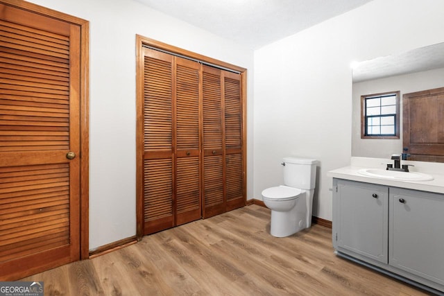 bathroom with toilet, baseboards, a closet, and wood finished floors