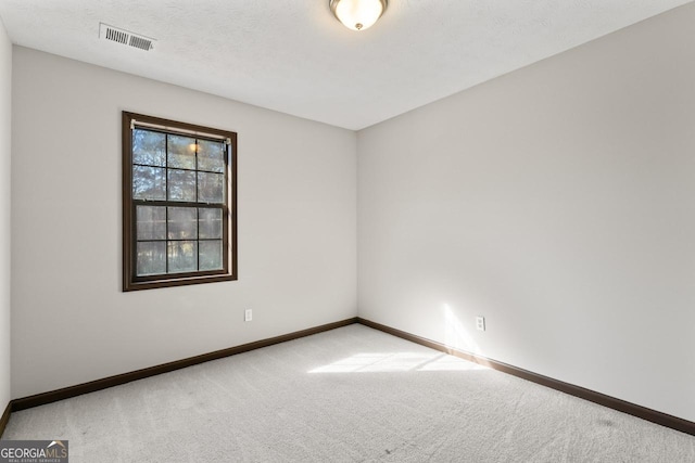 carpeted spare room featuring visible vents, a textured ceiling, and baseboards