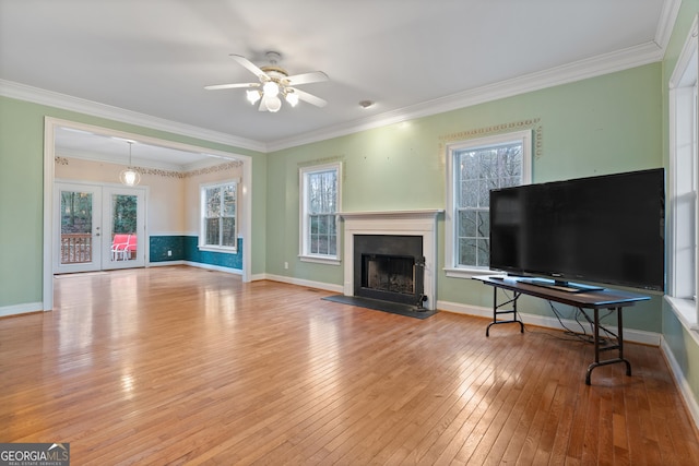 living room featuring wood-type flooring, ornamental molding, and a wealth of natural light