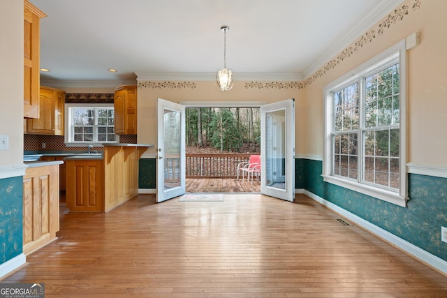 kitchen featuring french doors, ornamental molding, light wood-type flooring, and decorative light fixtures