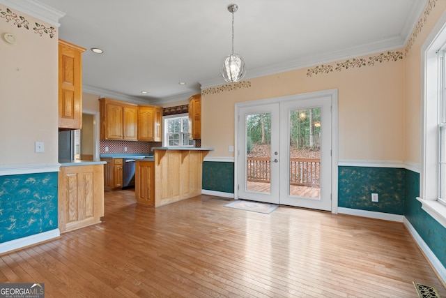 kitchen with a kitchen bar, decorative light fixtures, light wood-type flooring, ornamental molding, and kitchen peninsula