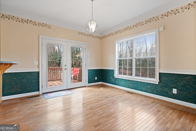 unfurnished dining area featuring hardwood / wood-style flooring, ornamental molding, plenty of natural light, and french doors