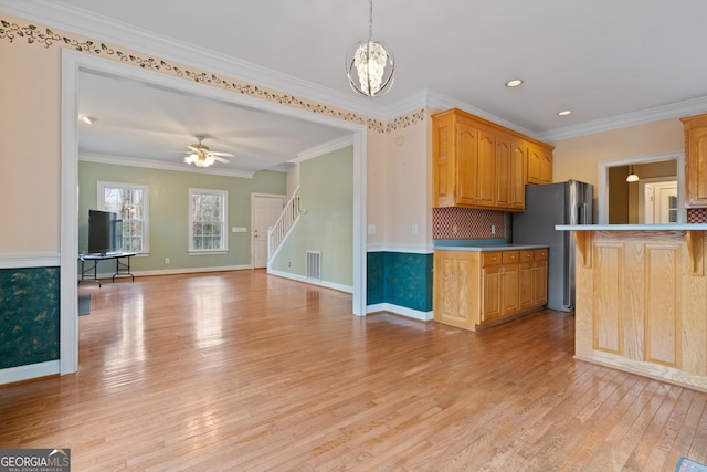 kitchen with ceiling fan with notable chandelier, stainless steel refrigerator, ornamental molding, light hardwood / wood-style floors, and decorative light fixtures