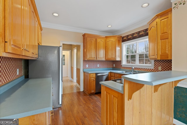 kitchen featuring sink, kitchen peninsula, stainless steel appliances, crown molding, and light hardwood / wood-style flooring