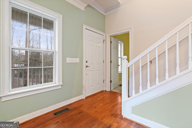 foyer entrance with wood-type flooring, ornamental molding, and plenty of natural light