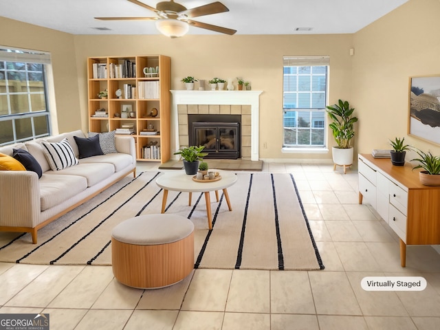 tiled living room featuring ceiling fan and a fireplace