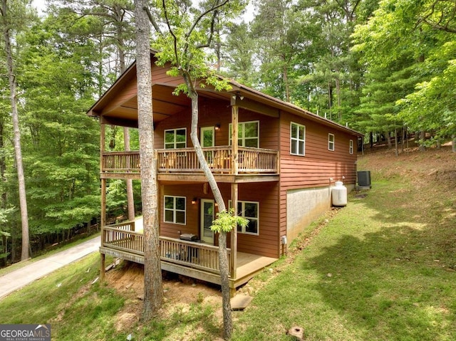 rear view of property featuring cooling unit, a yard, and a deck