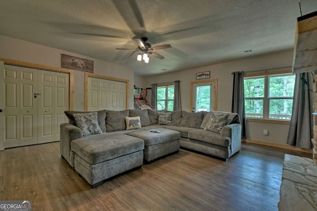 living room featuring hardwood / wood-style flooring, ceiling fan, and a textured ceiling