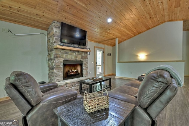 living room with hardwood / wood-style flooring, a stone fireplace, vaulted ceiling, and wooden ceiling