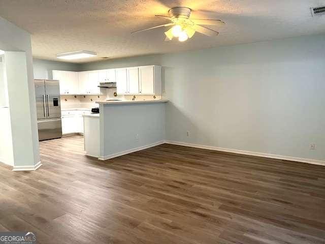 kitchen featuring dark wood-type flooring, a textured ceiling, white cabinets, high end refrigerator, and kitchen peninsula