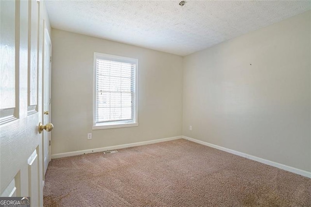 empty room with carpet floors and a textured ceiling