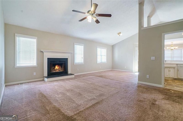 unfurnished living room with ceiling fan with notable chandelier, light carpet, and high vaulted ceiling