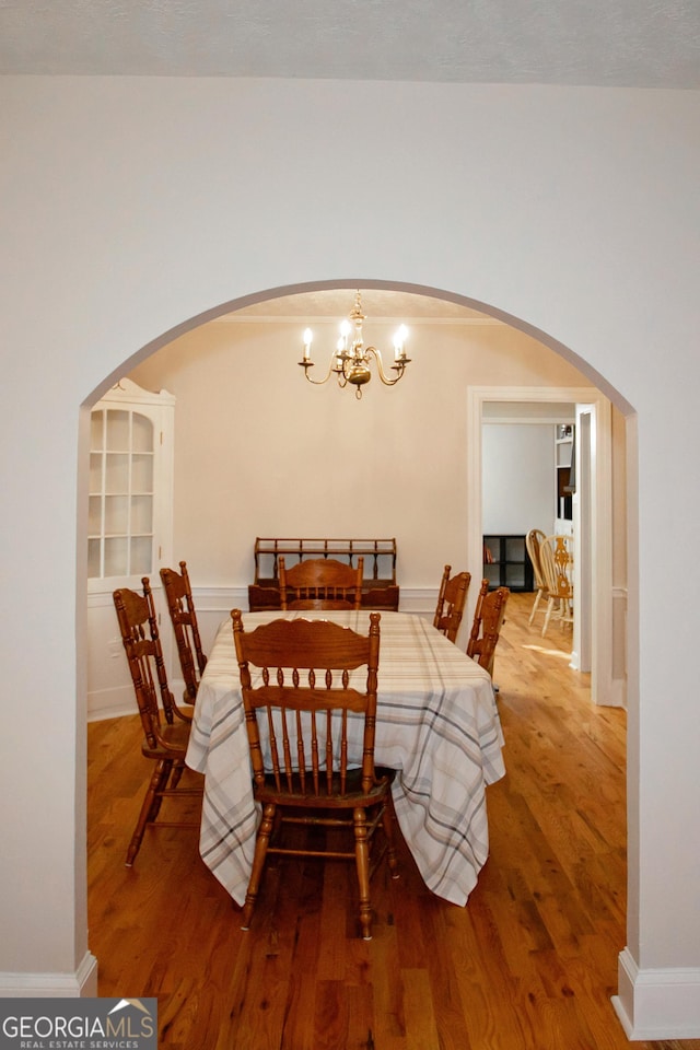 dining space with hardwood / wood-style floors and an inviting chandelier