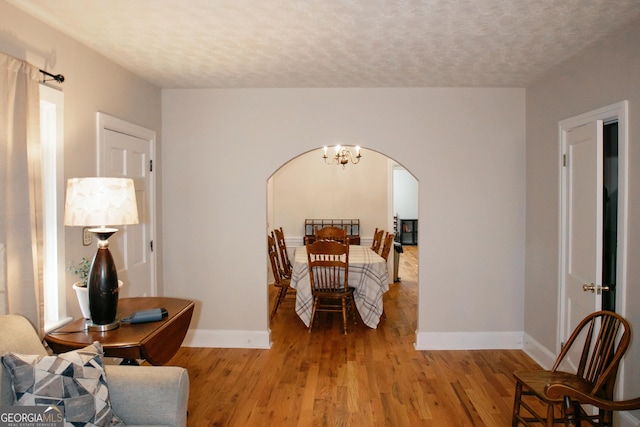 bedroom with a notable chandelier, a textured ceiling, and light wood-type flooring