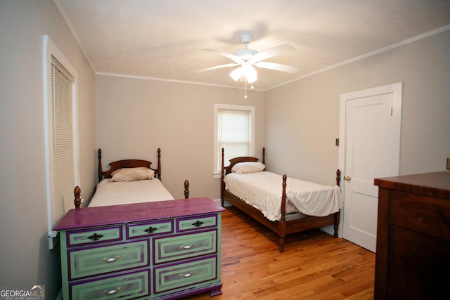 bedroom featuring crown molding, ceiling fan, light wood-type flooring, and a closet