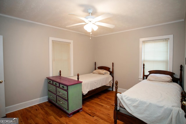 bedroom with dark wood-type flooring, ceiling fan, and ornamental molding