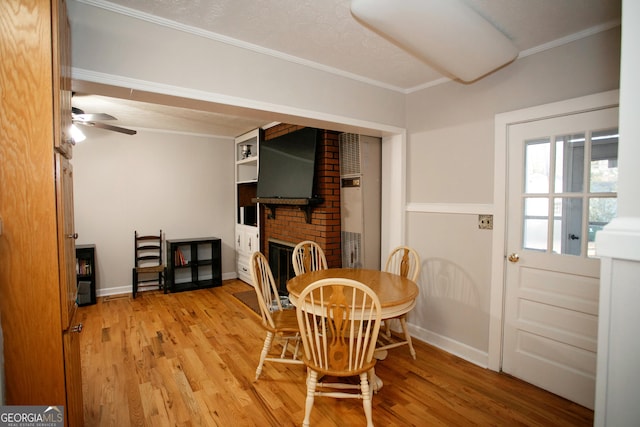 dining area with crown molding, ceiling fan, wood-type flooring, and a fireplace