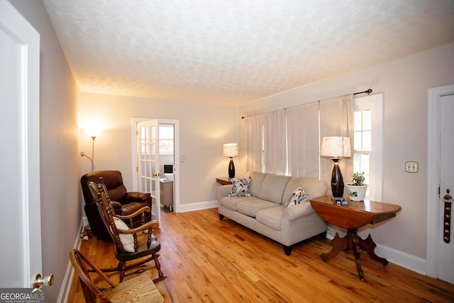 living room with a textured ceiling, light hardwood / wood-style floors, and a healthy amount of sunlight