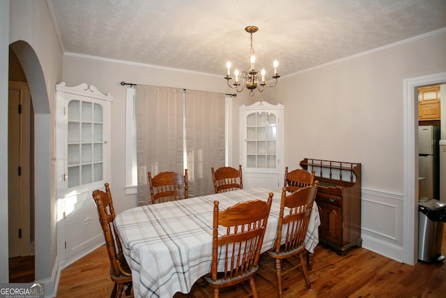 dining room with crown molding, a chandelier, hardwood / wood-style floors, and a textured ceiling