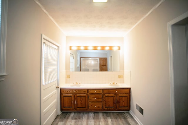 bathroom with ornamental molding, hardwood / wood-style floors, vanity, and backsplash