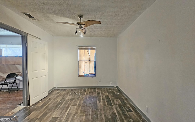 empty room featuring ceiling fan, dark hardwood / wood-style floors, and a textured ceiling