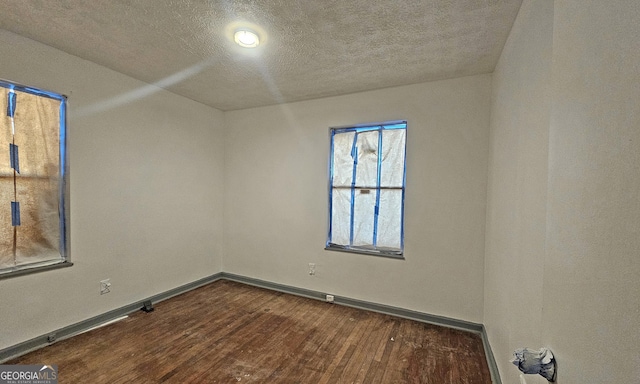 unfurnished room with dark hardwood / wood-style flooring and a textured ceiling