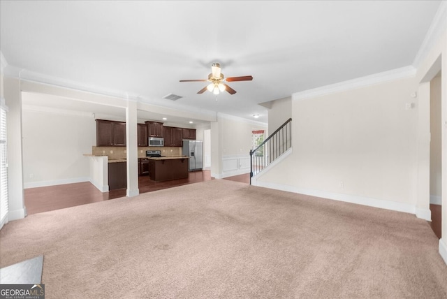 unfurnished living room featuring crown molding, ceiling fan, and dark colored carpet