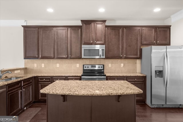 kitchen with stainless steel appliances, sink, light stone counters, and a kitchen bar