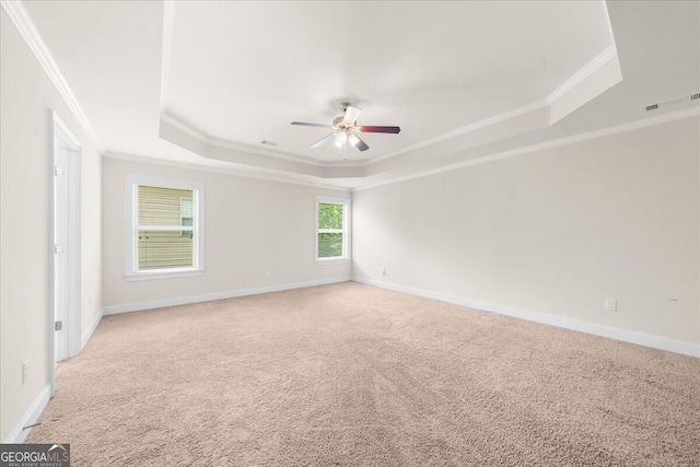 carpeted empty room featuring crown molding, ceiling fan, and a raised ceiling