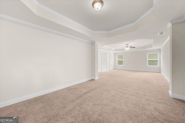 carpeted empty room featuring a raised ceiling, ornamental molding, and ceiling fan