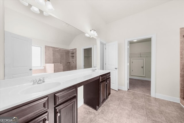 bathroom featuring tiled shower, vanity, and vaulted ceiling