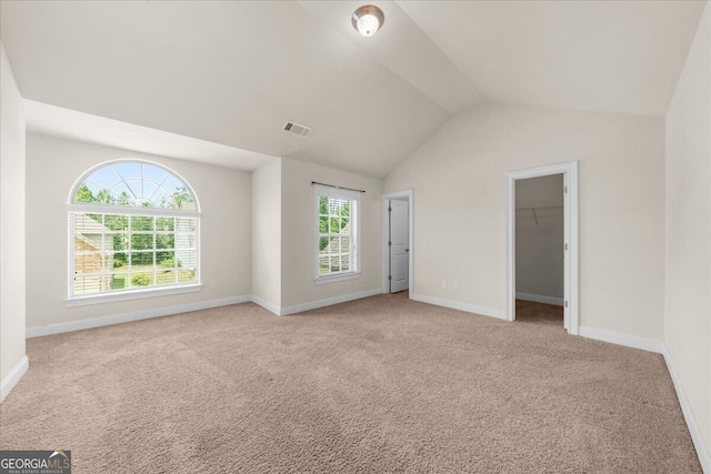 carpeted spare room with vaulted ceiling