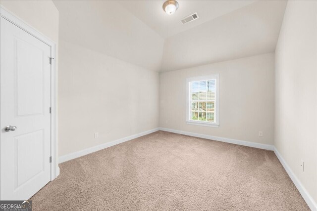 spare room featuring lofted ceiling and carpet floors