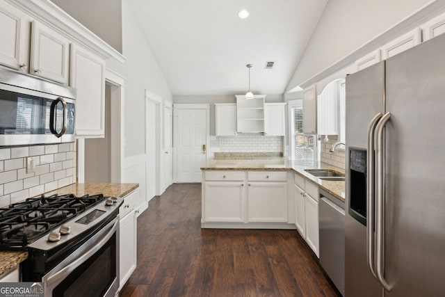 kitchen with lofted ceiling, sink, decorative light fixtures, stainless steel appliances, and white cabinets