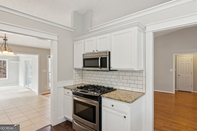 kitchen with stone counters, tasteful backsplash, white cabinetry, wood-type flooring, and stainless steel appliances