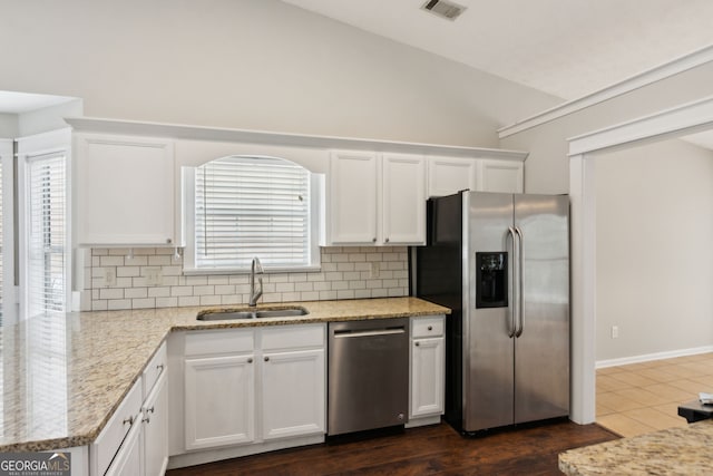 kitchen featuring white cabinetry, lofted ceiling, sink, backsplash, and stainless steel appliances